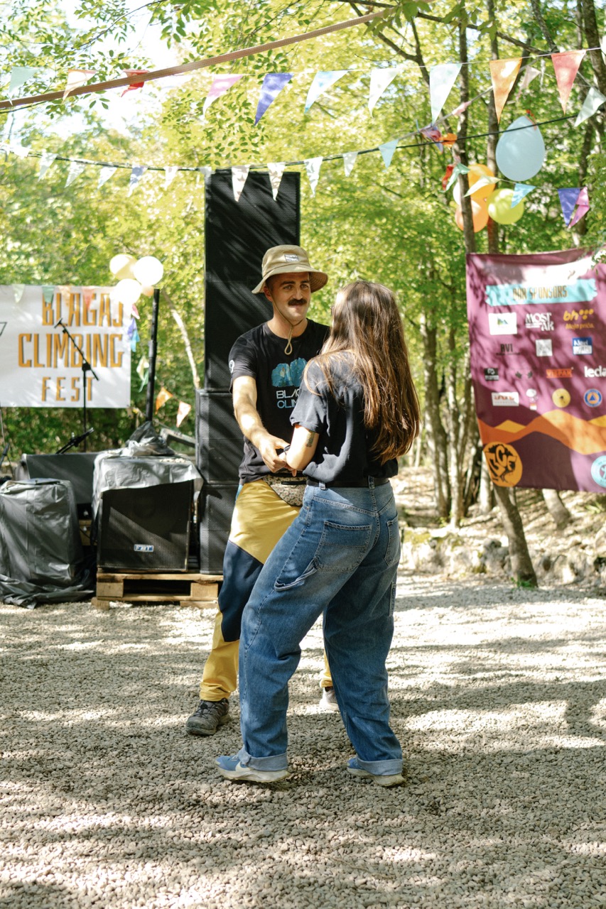 man and woman holding hands at an outdoor climbing festival decorated with colorful flags and balloons