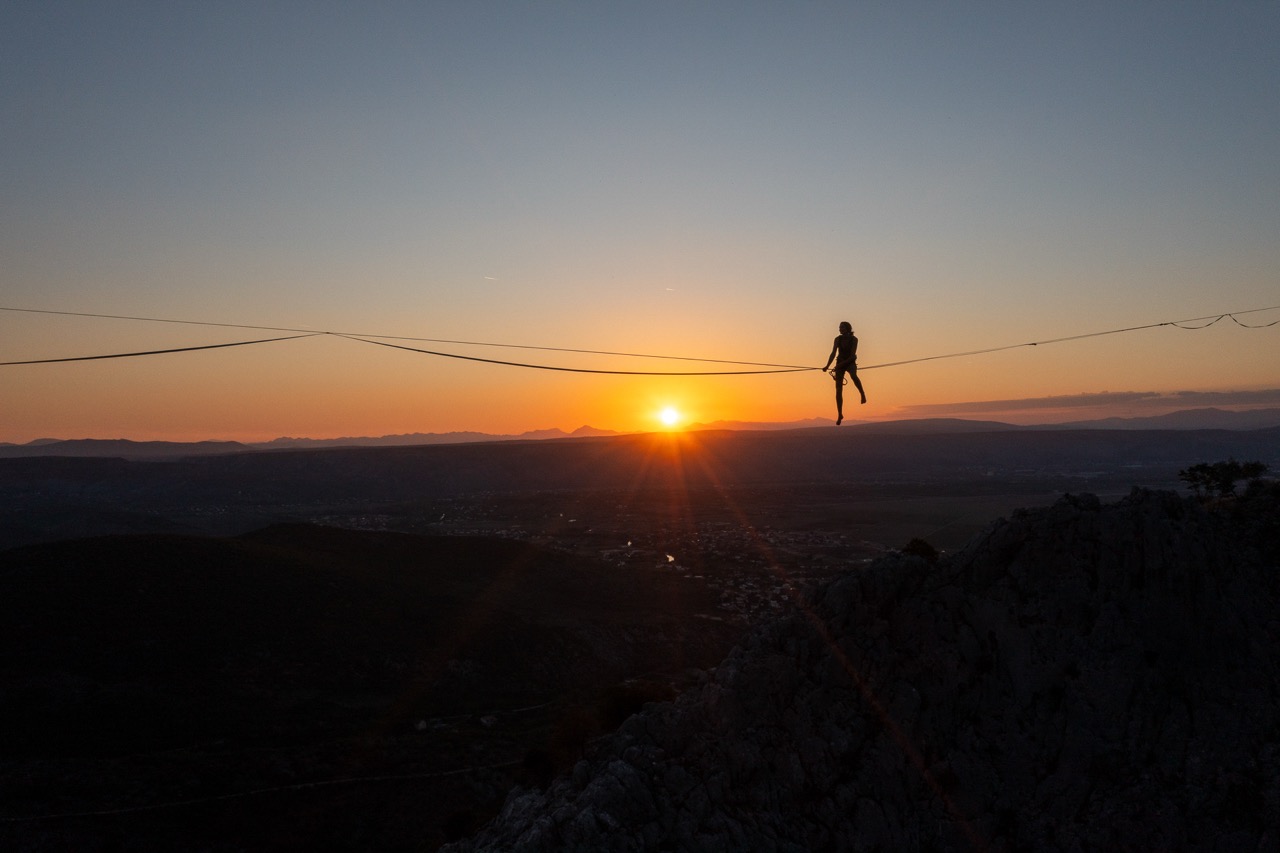 Highliner walking a line at sunset above the canyon